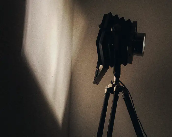 A camera on a tripod facing a lit wall, waiting for the take